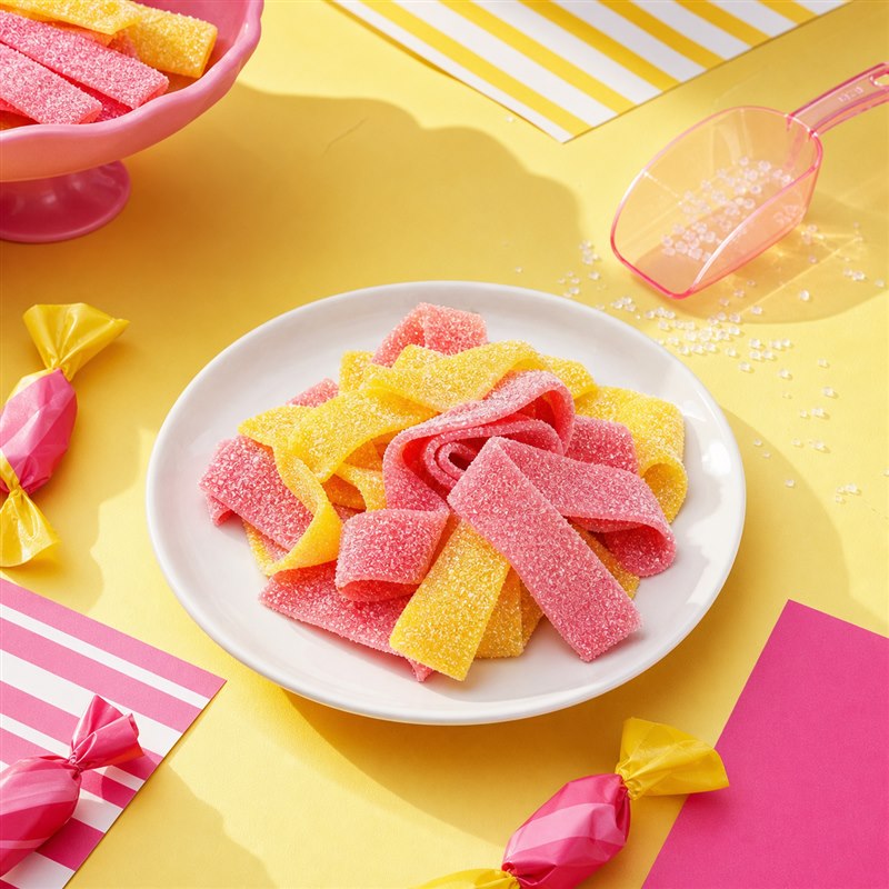 Pink and yellow Sour Strawberry Lemonade candy jerky in a colorful candy-shop scene